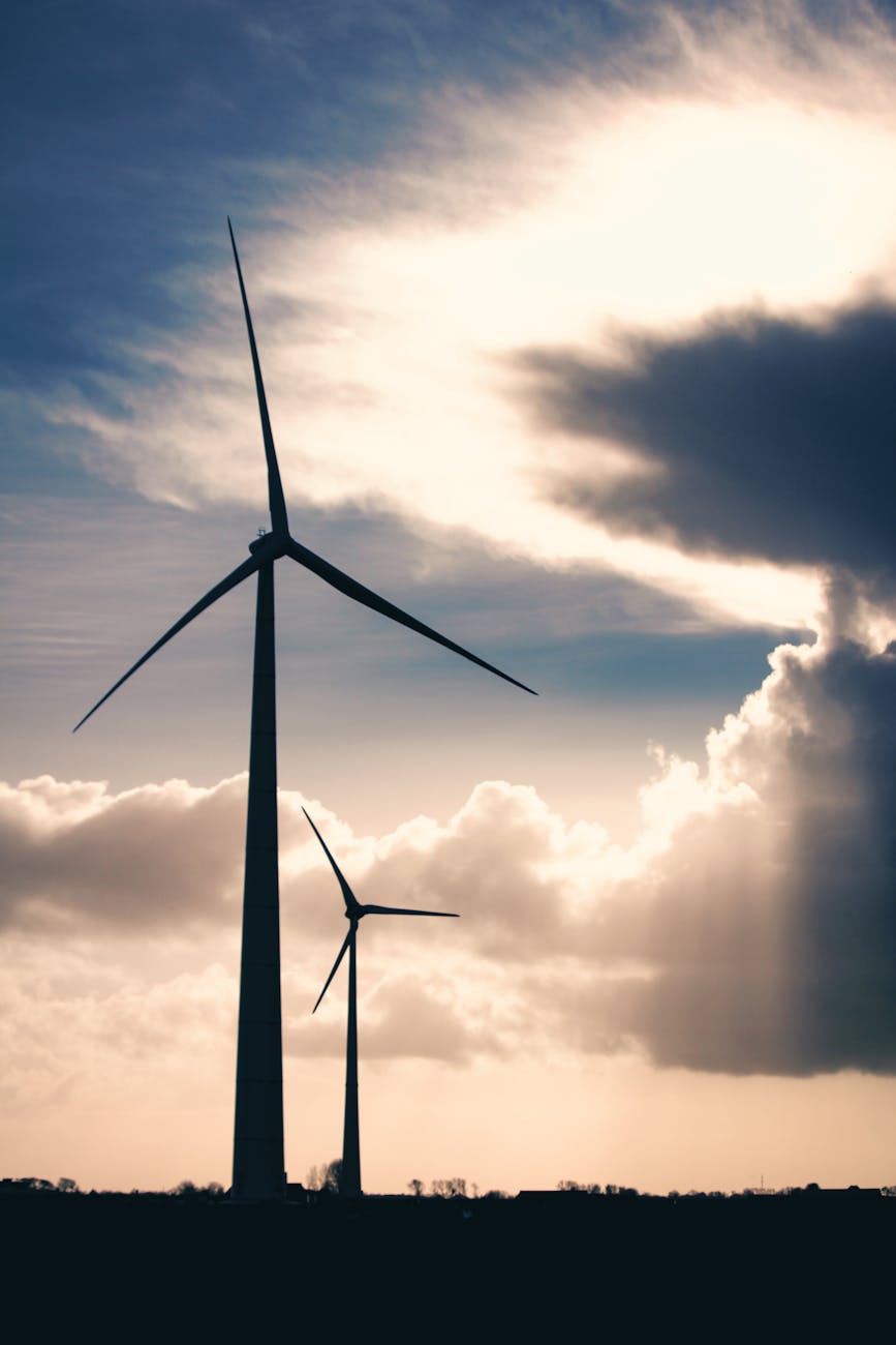 silhouette photo of two wind mills during golden hour